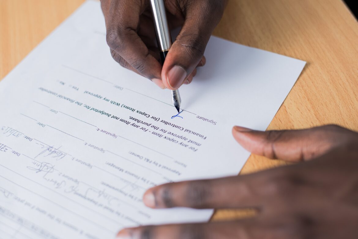 Man signing document/ Pexels