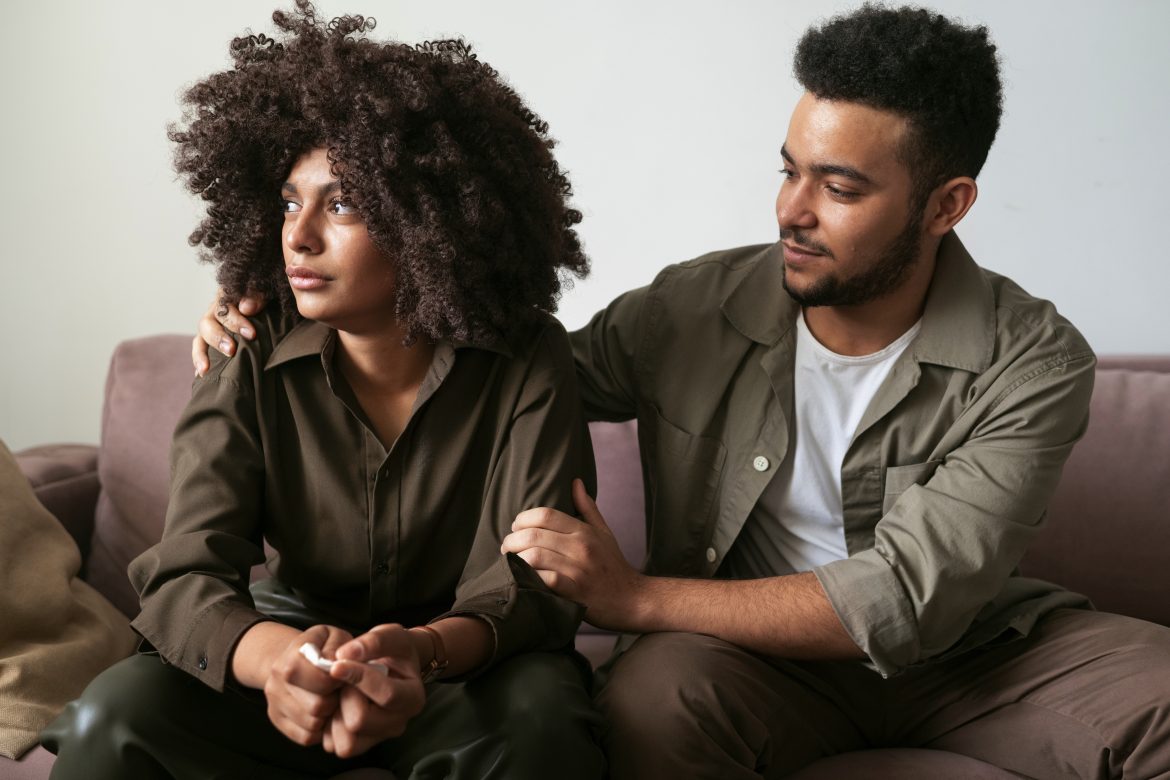 Despondent woman looks away while partner is trying to embrace her